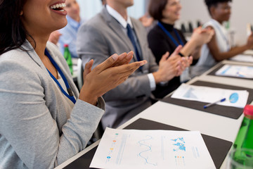 business and education concept - group of happy people applauding at international conference