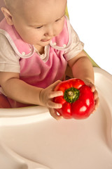 Cute little girl smiles while holding red bell pepper