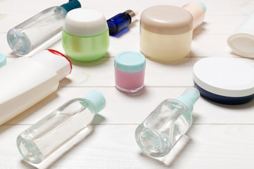 Close-up view of cosmetic bottles, jars, containers and sprays on white wooden background. Beauty concept with copy space