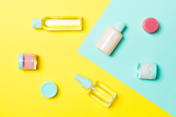 Top view of cosmetic containers, sprays, jars and bottles on yellow and blue background. Close-up view with empty space for your design