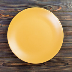 Yellow Round Plate on wooden table background. Top view, template for your design