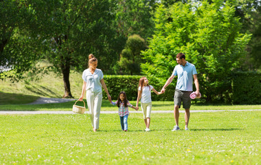 family, leisure and people concept - happy mother with picnic basket, father and two daughters walking in summer park