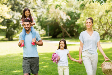 family, leisure and people concept - happy mother with picnic basket, father and two daughters...