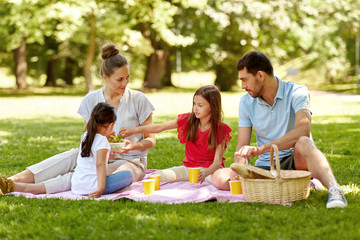 family, leisure and people concept - happy mother, father and two daughters having picnic at summer...