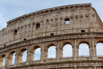 Obraz premium Detail of the Colosseum, under a blue sky with white clouds.