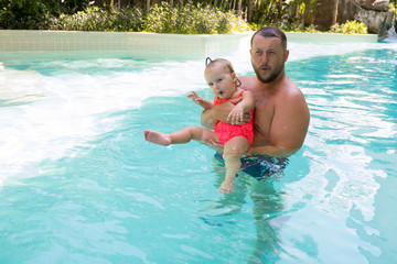 happy father swims in the pool with his daughter