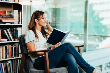 Fototapeta premium Attractive young female student choosing books in the bookstore