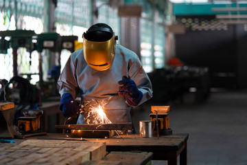 Industrial welder is welding metal part in the factory. - obrazy, fototapety, plakaty