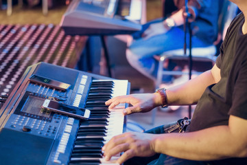 Musician play electronic keyboard synthesizers by using smartphone as guidelines for playing on the concert stage. Selective focus on smartphone.