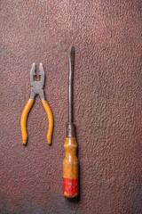 Screwdriver and pliers on rusty steel plate