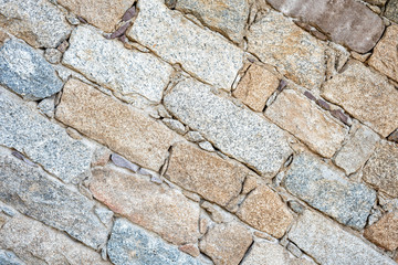 Detail of an old stone wall arranged in an irregular manner. Architecture constructions. Vintage background. Oblique lines.