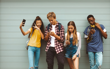 Teenage friends looking at their mobile phones - obrazy, fototapety, plakaty