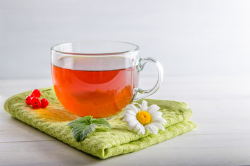 tea in a mug with berries and chamomile on a white background