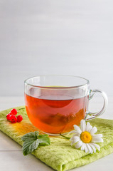 tea in a mug with berries and chamomile on a white background