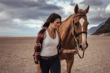 Obraz premium Woman walking with horse on the coast