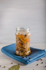 pickled mushrooms in a glass jar on a white background