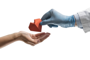 Doctor's hand gives a red paper heart to a woman. Image on isolated white background. Concept of...