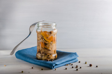 pickled mushrooms in a glass jar on a white background