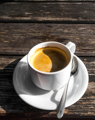 cup of coffe, image shape from shadow Yin Yang, on wooden background. White ceramic cup, stylish toning, copy space