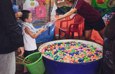 Little boy received the prize from winning fishing and scooping colourful eggs game