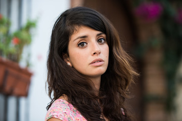 Portrait of a young woman in a tipical spanish yard looking into the camera.