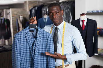 Male tailor demonstrating of fashionable suit in apparel shop