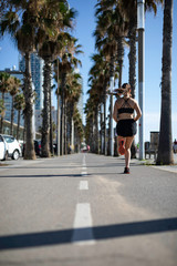 Beautiful woman in sport clothes running on the bike lane at the seafront in Barcelona (SPAIN)