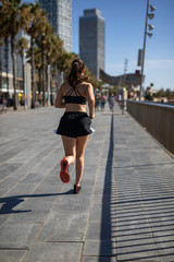 Beautiful woman in sport clothes running on the seafront in Barcelona (SPAIN)