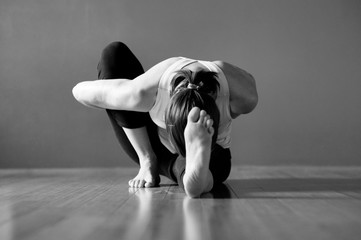 Black and white yoga woman in deep asana pose Janu Sirsasana a sitting bound forward fold. 