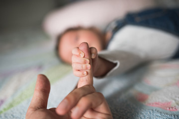 Child holds finger. Baby hand gently holding adult's finger.