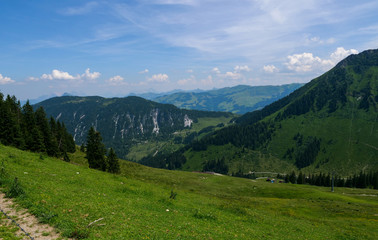 Fototapeta na wymiar Beautiful alpine landscape with green meadows, alpine cottages and mountain peaks, Alpinolino, Westendorf Tyrol Alps, Austria