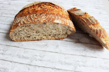 crusty vintage bread with one cut loaf on light wooden background with copy space