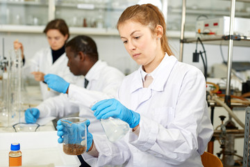 Serious woman lab  scientist in glasses working with reagents and test tubes