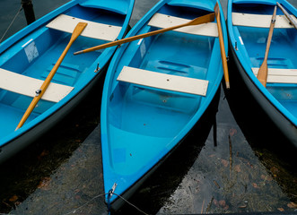 bright blue and white rowboats in dark lake water