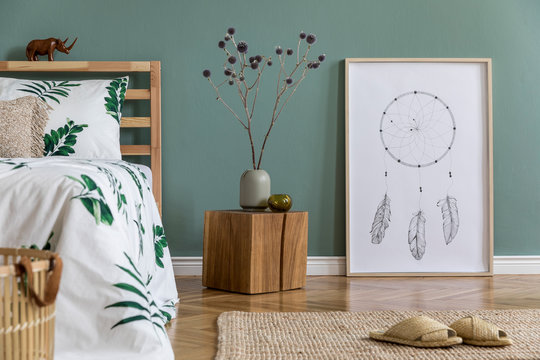 Stylish and deign composition of bedroom interior with wooden bed, mock up poster frame, cube, basket, vase with flowers and elegant accessories. Beautiful bed sheets, blankets and pillow. Template.