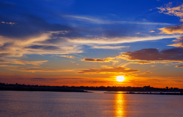 Fototapeta na wymiar Beautiful Sunset in the sky with sky blue and orange light of the sun through the clouds in the sky, Orange and red dramatic colors over the sea. - Image