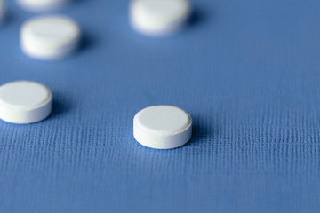 White tablets scattered on a blue background close up