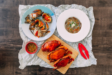 Top view of Fish Sauce-Fermented raw Prawns and Sea Crab with Pickled Crab Eggs and Steamed Giant Mud Crabs served with Thai style spicy seafood sauce.