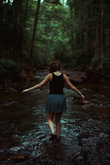 Young woman walking away in stream 
