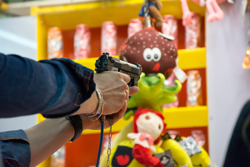 Fototapeta na wymiar Close Up of Hand of a Man Shooting with an Air Pistol at Luna Park