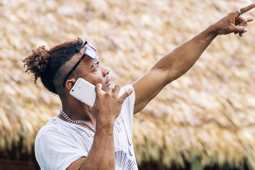 Naklejka premium side view of Handsome african american guy in trendy haircut talking on the phone