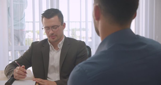 Closeup portrait of two attractive businessmen having a job interview in the office indoors on the workplace