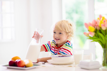 Child eating breakfast. Kid with milk and cereal.