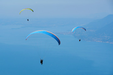 Paraglider flying over the Garda Lake (Lago di Garda or Lago Benaco). Paragliding on Monte Baldo. Panorama of the gorgeous Garda lake surrounded by mountains, Malcesine, Italy
