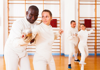 fencer practicing movements with african american trainer