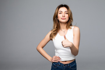 Happy woman showing thumb up over gray background.