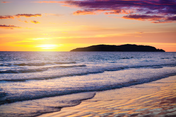 Sunset at tropical beach. Ocean waves by sunrise.