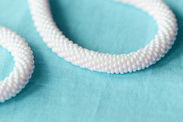 White beaded necklace on a blue textile background close up