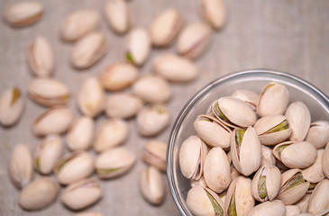 Green and tasty pistachios in a transparent bowl. Healthy and nutritious snack filled with vitamins...