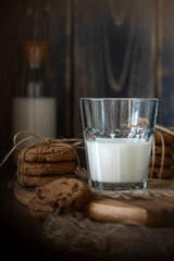 Chocolate chip cookies and milk on wooden background with vignette